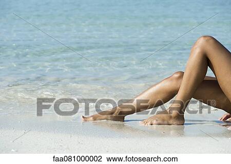 Stock Image - Woman's legs on beach, low section. Fotosearch