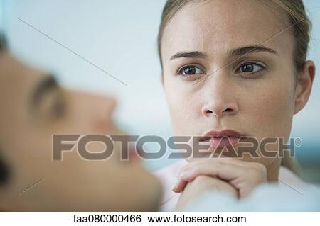 Worried woman looking at sick man in foreground View Large Photo Image Stock Photograph - Worried woman looking at sick man in foreground. Fotosearch