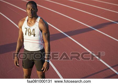 Stock Image - Young athlete standing on running track, portrait. Fotosearch