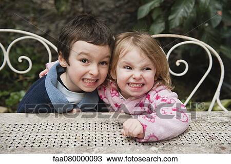 Stock Image - Young brother and sister smiling together outdoors, portrait. Fotosearch