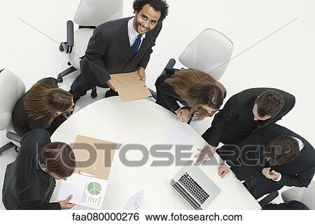 Stock Photograph - Young businessman giving presentation at meeting. Fotosearch