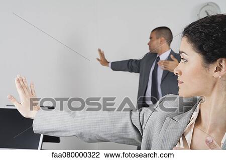 Stock Image - Young businesswoman and businessman exercising in office. Fotosearch