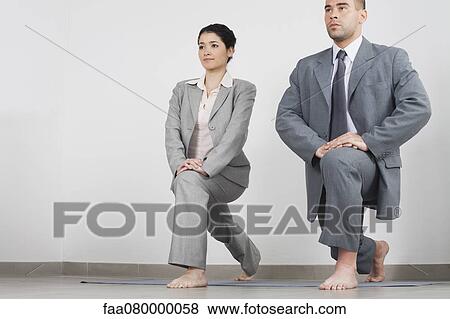 Young businesswoman and businessman doing yoga lunge side by side in office View Large Photo Image Stock Photo - Young businesswoman and businessman doing yoga lunge side by side in office. Fotosearch