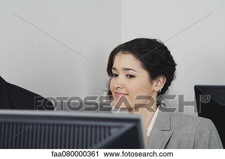 Stock Image - Young businesswoman looking at computer monitor. Fotosearch
