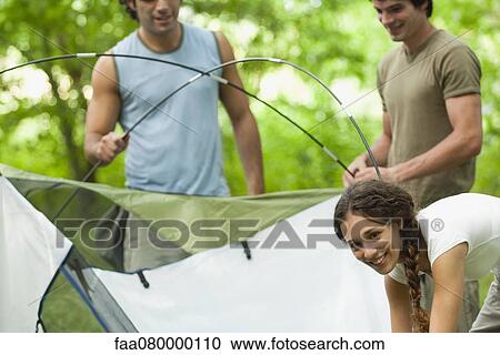 Stock Image - Young campers setting up tent. Fotosearch