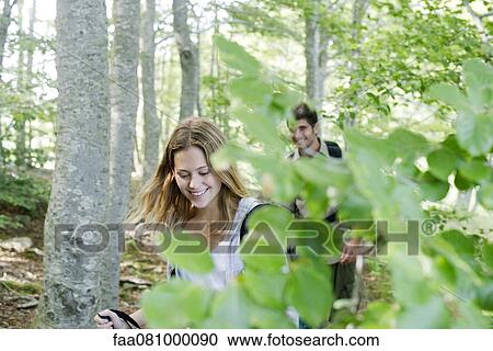 Stock Image - Young couple hiking in woods. Fotosearch