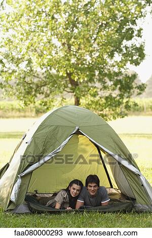 Stock Image - Young couple lying together in tent. Fotosearch