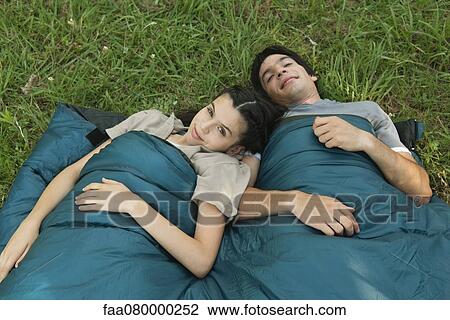 Young couple sharing sleeping bag in field View Large Photo Image Stock Image - Young couple sharing sleeping bag in field. Fotosearch