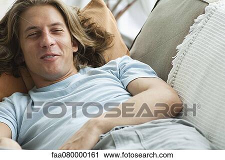 Stock Image - Young man relaxing on sofa. Fotosearch