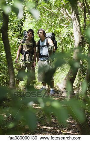 Stock Image - Young men hiking in woods. Fotosearch