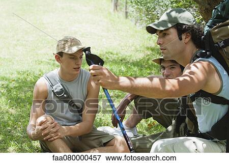 Young men relaxing on grass during hike View Large Photo Image Stock Photo - Young men relaxing on grass during hike. Fotosearch