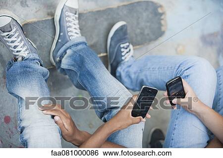 Stock Photograph - Young men using cell phones, cropped. Fotosearch