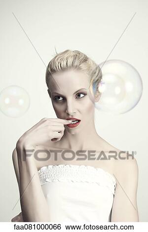 Stock Photograph - Young woman biting finger, portrait. Fotosearch