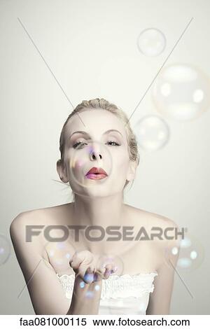 Stock Photography - Young woman blowing bubbles. Fotosearch