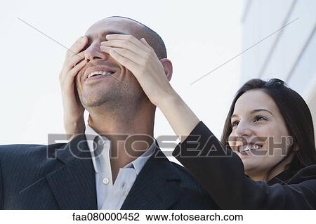 Young woman covering man's eyes, low angle view View Large Photo Image Stock Image - Young woman covering man's eyes, low angle view. Fotosearch