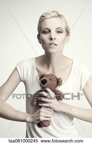 Stock Photography - Young woman gripping teddy bear, portrait. Fotosearch