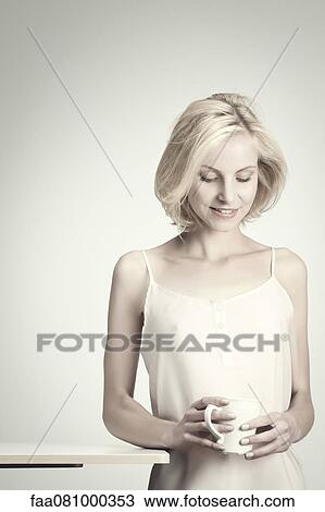Stock Image - Young woman holding coffee cup, portrait. Fotosearch