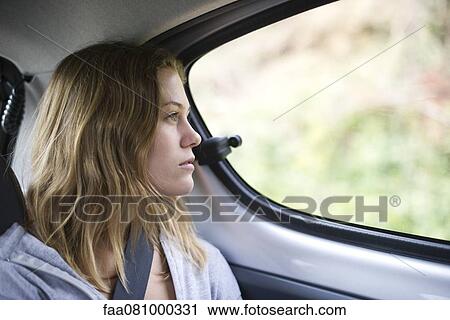 Stock Image - Young woman in car looking out of window. Fotosearch