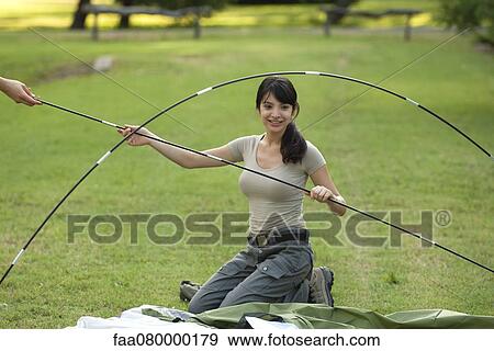 Stock Photo - Young woman putting tent poles together. Fotosearch