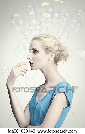 Stock Image - Young woman surrounded by bubbles, portrait. Fotosearch