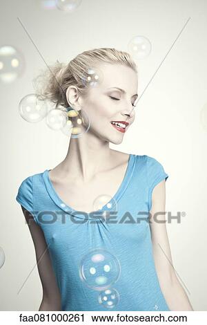 Stock Image - Young woman surrounded by bubbles. Fotosearch