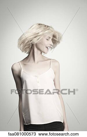 Stock Image - Young woman tossing hair with eyes closed, portrait. Fotosearch