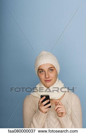 Young woman using cell phone, looking up in thought View Large Photo Image Stock Photo - Young woman using cell phone, looking up in thought. Fotosearch