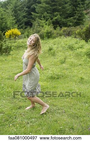 Young woman walking on meadow with barefeet View Large Photo Image Stock Photo - Young woman walking on meadow with barefeet. Fotosearch