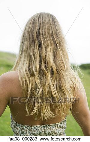 Stock Image - Young woman with long blonde hair, rear view. Fotosearch