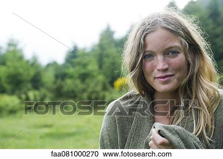 Stock Image - Young woman wrapped in blanket, portrait. Fotosearch