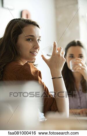 Stock Photograph - Young women drinking water in restaurant. Fotosearch