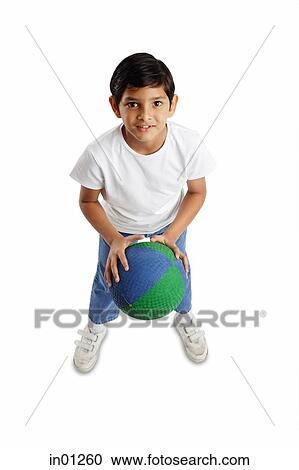 Stock Image - Boy holding basketball, facing forward. Fotosearch