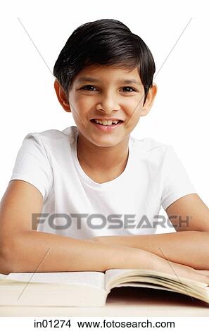 Picture - Boy leaning on book, smiling at camera. Fotosearch