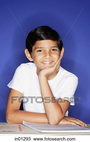 Stock Image - Boy looking at camera, hand on chin. Fotosearch