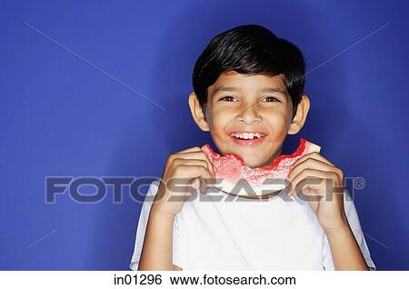Boy looking at camera, holding half eaten slice of watermelon View Large Photo Image Stock Photograph - Boy looking at camera, holding half eaten slice of watermelon. Fotosearch