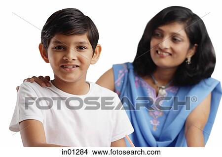 Boy looking at camera, mother behind him with her hand on his shoulder View Large Photo Image Picture - Boy looking at camera, mother behind him with her hand on his shoulder. Fotosearch
