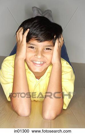 Boy lying on floor, head in hands View Large Photo Image Stock Image - Boy lying on floor, head in hands. Fotosearch