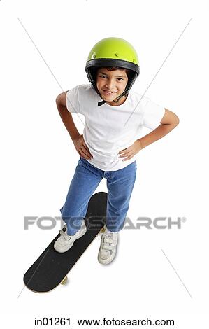 Stock Image - Boy with helmet, standing on skateboard, hand on hip. Fotosearch