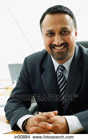 Businessman at desk, looking at camera, smiling View Large Photo Image Picture - Businessman at desk, looking at camera, smiling. Fotosearch