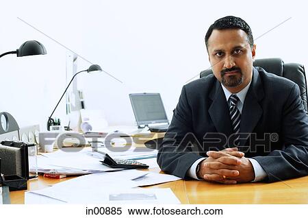 Stock Photography - Businessman at desk, looking at camera. Fotosearch