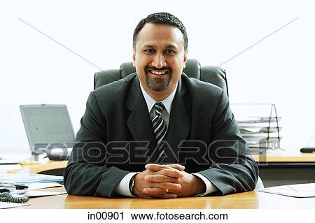 Businessman at desk, smiling at camera, hands clasped View Large Photo Image Stock Image - Businessman at desk, smiling at camera, hands clasped. Fotosearch