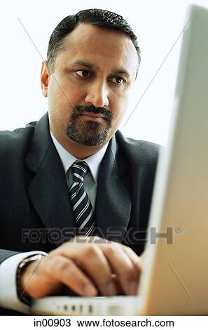 Stock Image - Businessman at desk, using laptop. Fotosearch