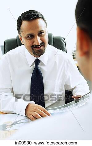 Stock Image - Businessman facing another person, over the shoulder view. Fotosearch