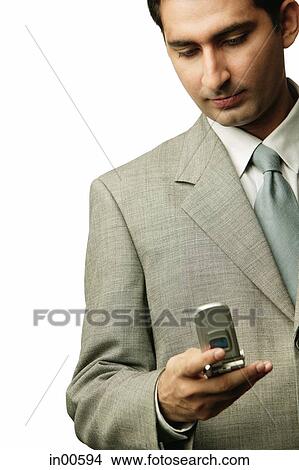 Businessman holding mobile phone, looking down View Large Photo Image Picture - Businessman holding mobile phone, looking down. Fotosearch