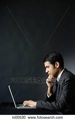 Businessman in front of laptop, hand on chin View Large Photo Image Stock Image - Businessman in front of laptop, hand on chin. Fotosearch