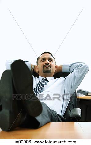 Businessman in office, hands behind head, feet on desk View Large Photo Image Stock Photograph - Businessman in office, hands behind head, feet on desk. Fotosearch