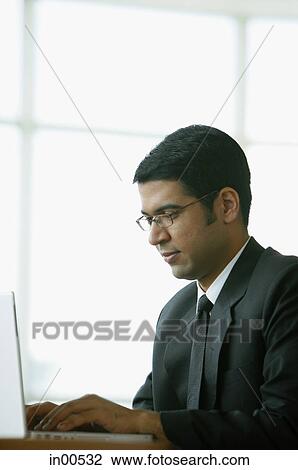 Businessman in office, using laptop View Large Photo Image Stock Image - Businessman in office, using laptop. Fotosearch