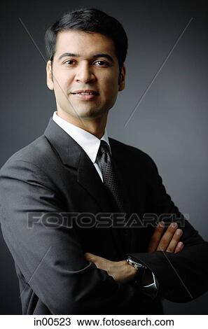 Stock Image - Businessman looking at camera, arms crossed, portrait. Fotosearch