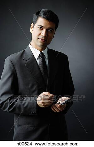 Picture - Businessman looking at camera, holding PDA. Fotosearch