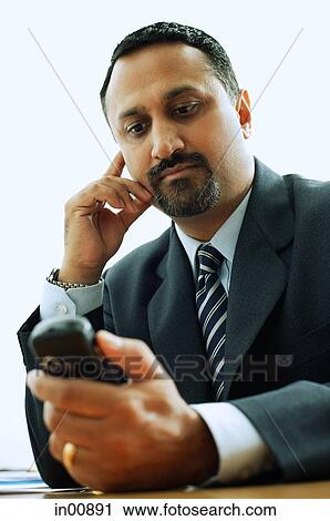 Businessman looking at PDA phone View Large Photo Image Stock Image - Businessman looking at PDA phone. Fotosearch